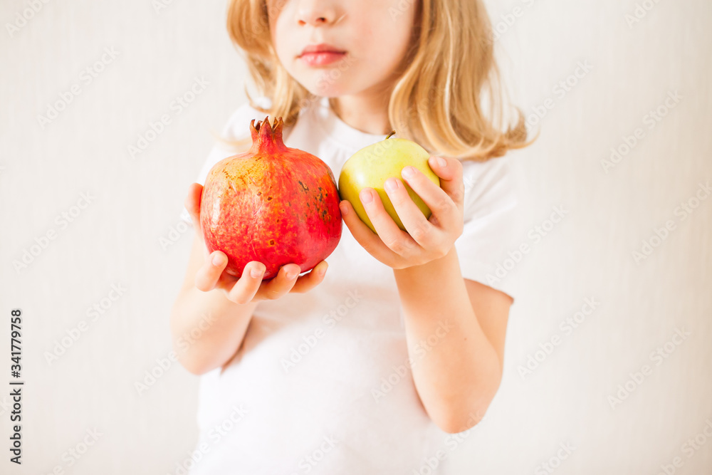 Little girl holding a pomegranate and apple. Symbol of the Jewish New Year. Rosh ha Shana. Little girl holding a pomegranate and apple. Symbol of the Jewish New Year. Rosh ha Shana.