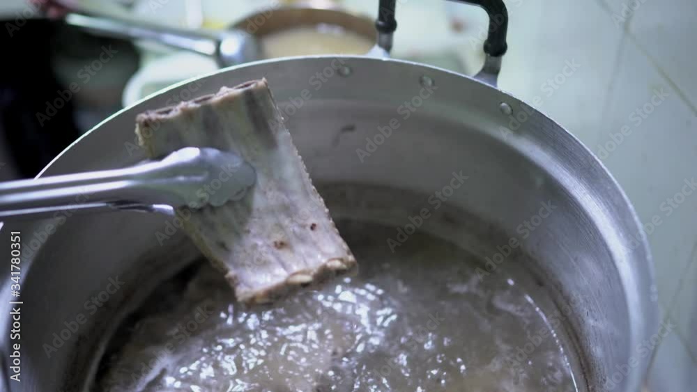Close up scene of cooking Bak Kut Teh by checking the pork ribs if its cooked, food processing, Malaysian and Singaporean traditional dish, cooking step, food preparation, the famous dish. Close up scene of cooking Bak Kut Teh by checking the pork ribs if its cooked, food processing, Malaysian and Singaporean traditional dish, cooking step, food preparation, the famous dish.