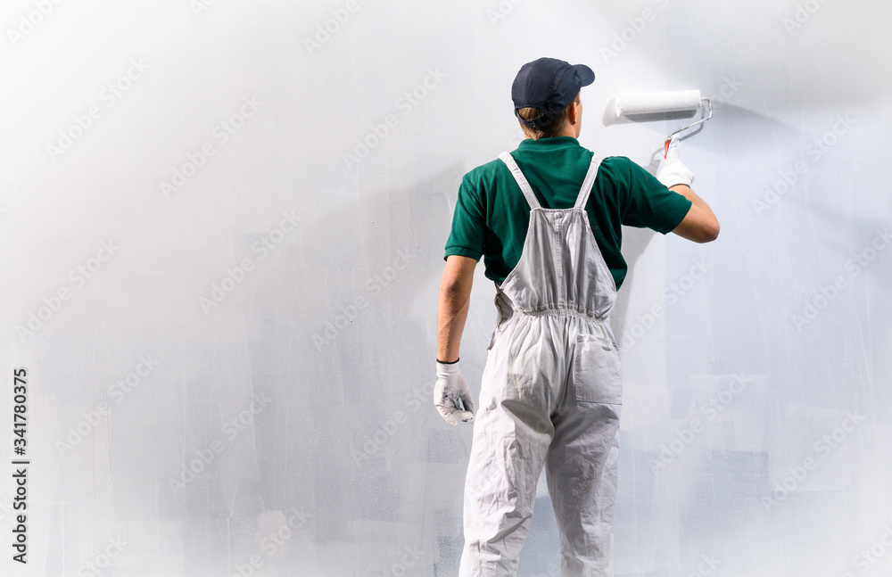 Fototapeta premium Man painting a wall in white color