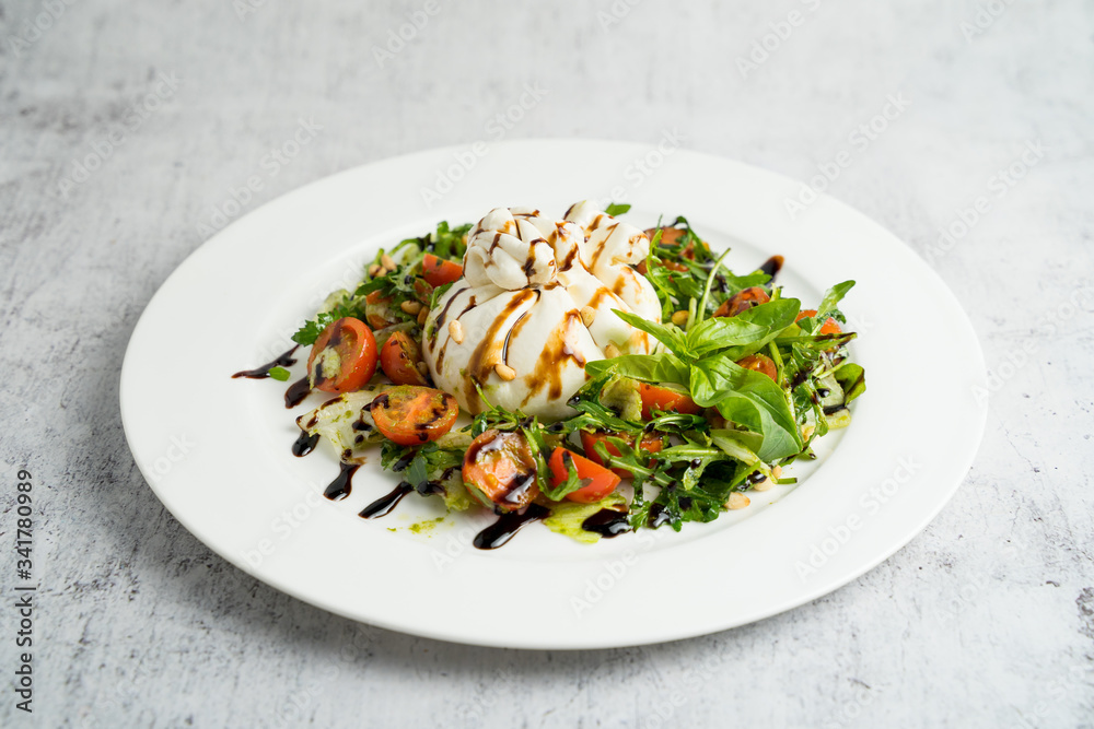 Buffalo burrata cheese with vegetables and herbs on a plate Buffalo burrata cheese with vegetables and herbs on a plate