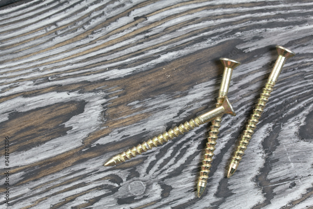 Several yellow metal screws. They lie on pine brushing boards painted black. World Labor Day. Several yellow metal screws. They lie on pine brushing boards painted black. World Labor Day.