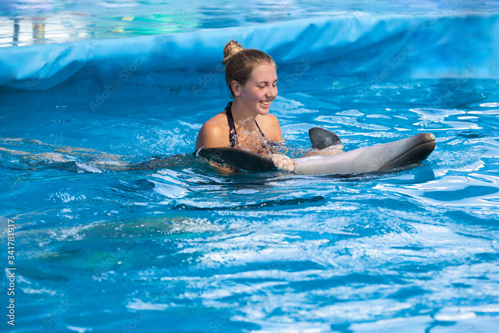 happy young woman swimming with dolphin