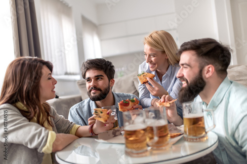 Group of friends enjoying pizza and beer.