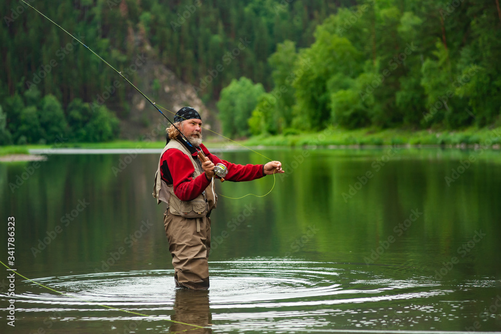 fly fishing angler makes cast while standing in water fly fishing angler makes cast while standing in water