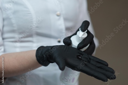 medical worker in black medical gloves pours an antiseptic on his hands © sun_house_ann