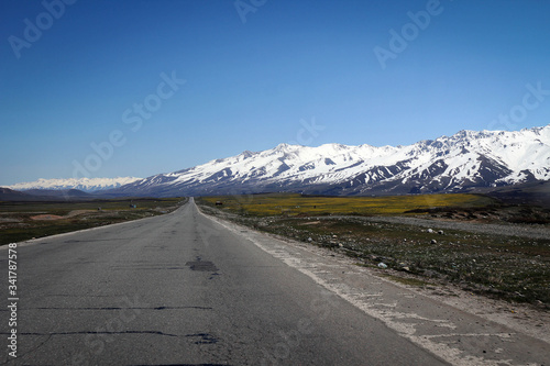 Endless road to snowy mountains  Tian Shan range  Kyrgyzstan