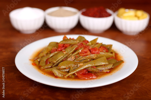 perfect turkish food green beans spicy on white plate close up on wooden table