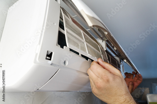 maintenance of air conditioner split system. man's hand holds inner filter from air conditioner, cleaning from dust and dirt for healthy living