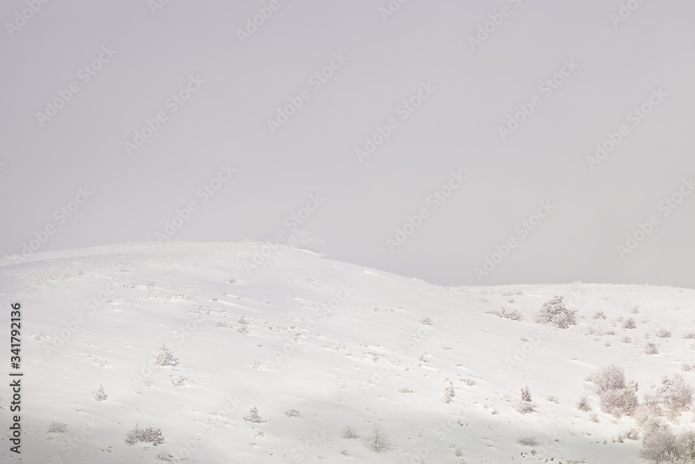 Beautiful, abstract, soft view of snow covered mountain highlands visible through the fog