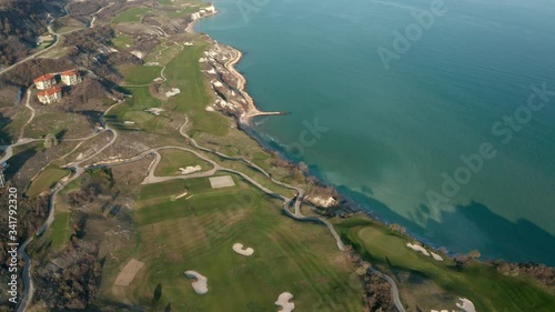 Panoramic video of picturesque landscape with green hills, golf fields and buildings near the rocky coastline of the Black sea, Thracian Cliffs golf and beach resort, Bulgaria.