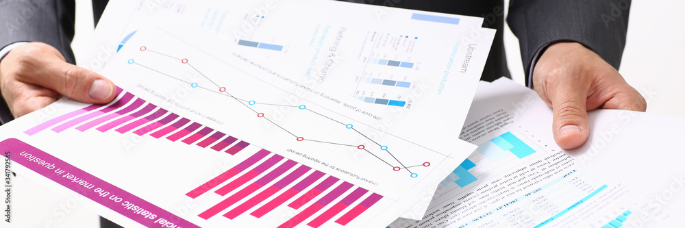 Fototapeta premium Male hand holding document with graph on seminar. Bank credit, loan money, invest, tax situation review, income calculation form, white collar train, investment audit, board members session concept