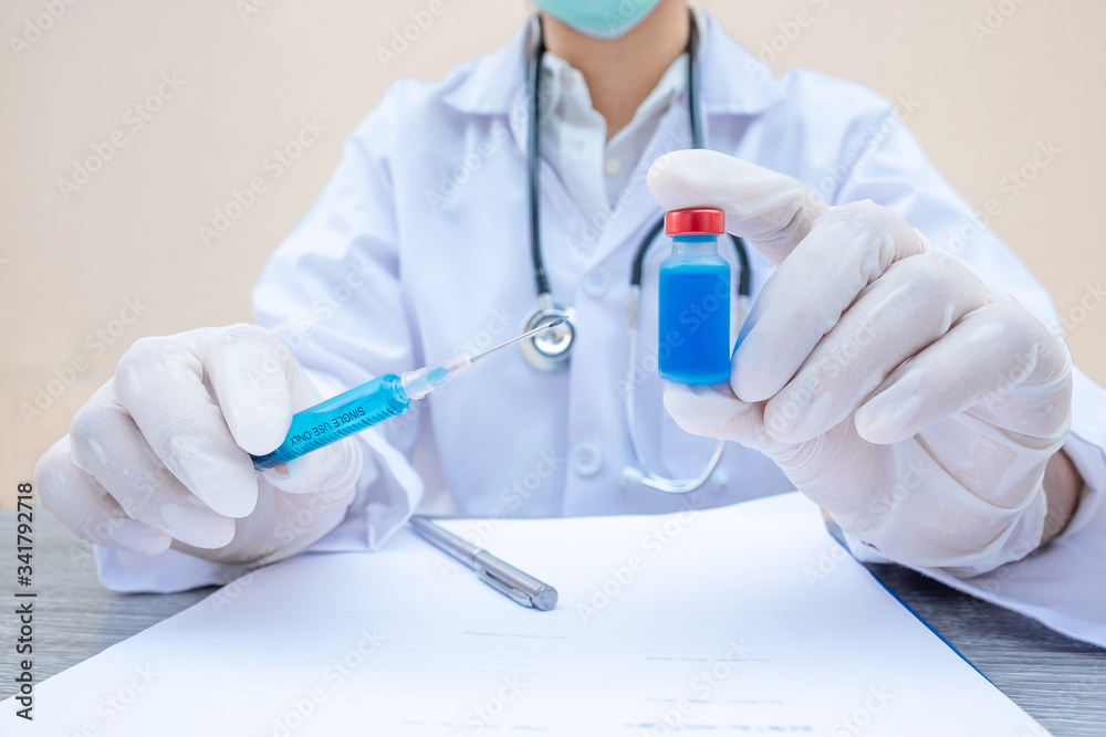 The doctor's hand is holding a blue serum tube and syringe The doctor's hand is holding a blue serum tube and syringe
