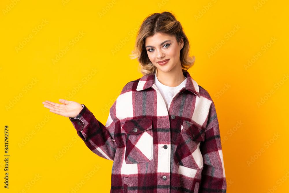 Young Russian woman isolated on yellow background extending hands to the side for inviting to come Young Russian woman isolated on yellow background extending hands to the side for inviting to come