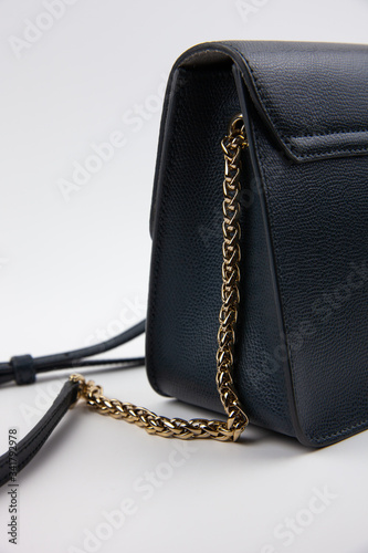 Blue crossbody bag with a metal gold handle on a white background. The rich blue color in combination with gold.