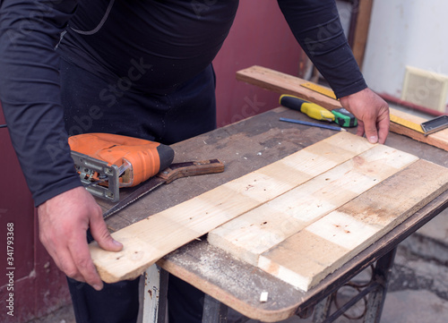 The carpenter works with wood on his workspace
