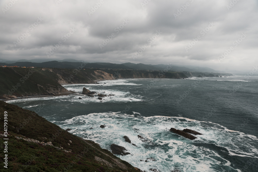 Cabo de Vidio en Cudillero, Asturias. Plano general un dia nublado de verano con marea revuelta 