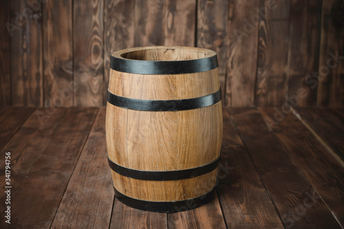 There is a wooden barrel on the background of brown boards.
