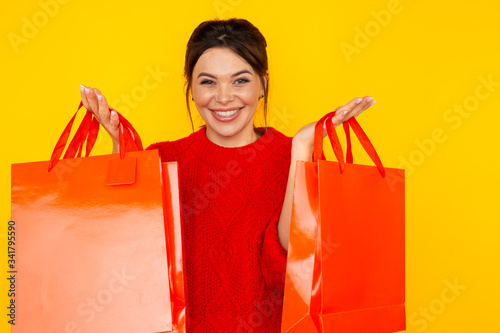 Nice smiling woman with shopping bags in the yellow studio