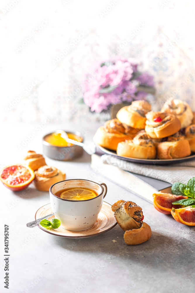 Homemade baking. Traditional bun with poppy seeds and sugar and a cup with tea. Homemade baking. Traditional bun with poppy seeds and sugar and a cup with tea.