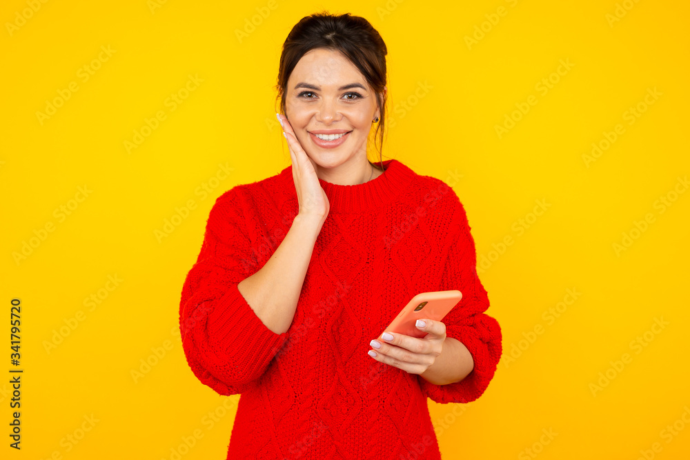 Glad pretty woman in the red clothes using phone isolated in the yellow room Glad pretty woman in the red clothes using phone isolated in the yellow room