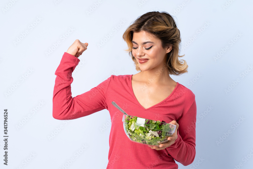 Teenager woman with salad isolated on blue background Teenager woman with salad isolated on blue background