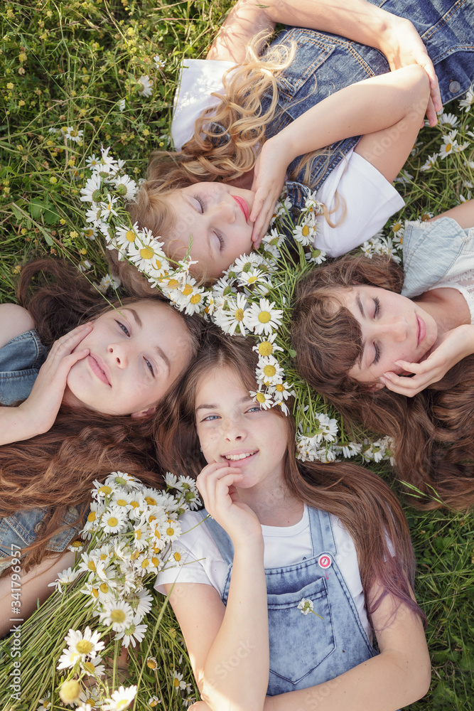 Fototapeta premium Four Teen girls enjoys spring in daisy field.
