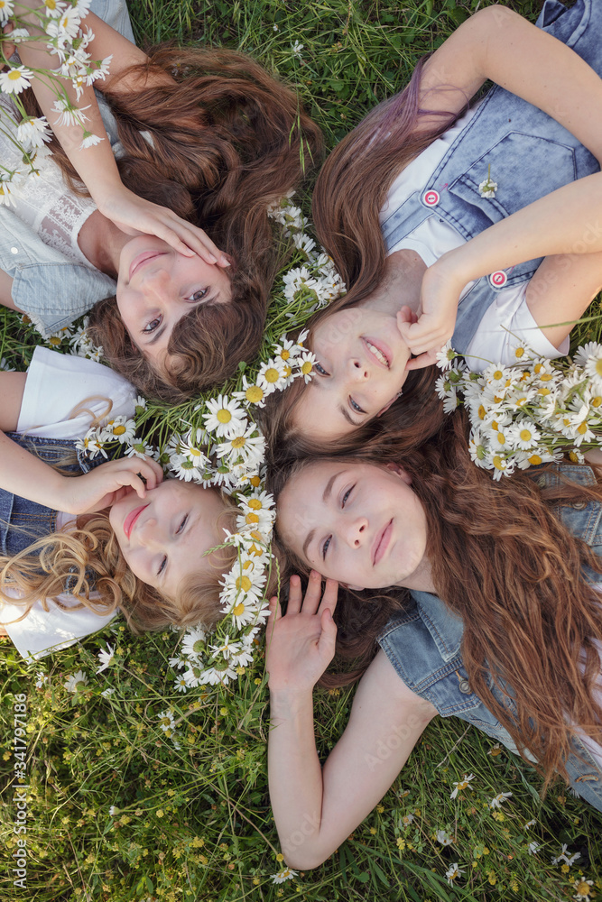 Fototapeta premium Four Teen girls enjoys spring in daisy field.