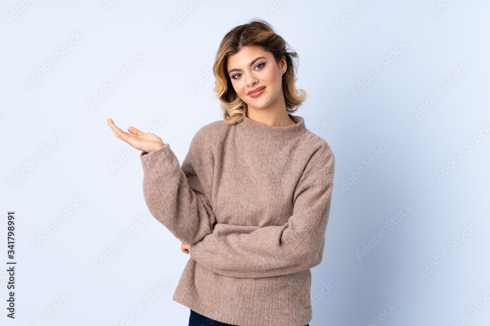 Young Russian woman isolated on blue background extending hands to the side for inviting to come Young Russian woman isolated on blue background extending hands to the side for inviting to come