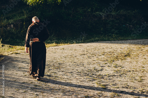 Catholic monk in robes praying in the woods. Copy space