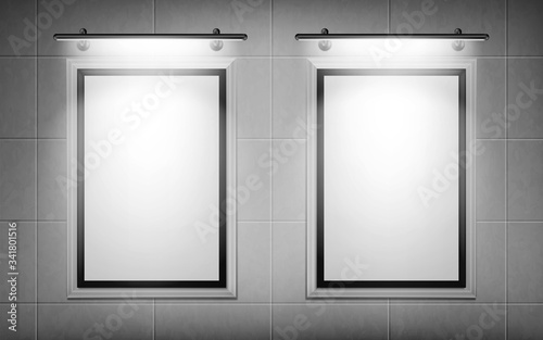 Blank movie posters illuminated by spotlights. Vector realistic mockup of white picture frames on gray tiled wall in cinema, theater or gallery. Empty advertising banners with black border and lamps