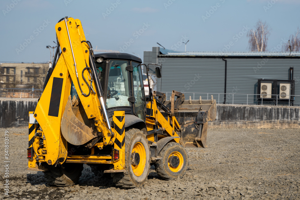 Yellow wheel loader Excavator machine working at construction site with a sand and gravel. Preparing of the fundament for a asphalting. Road construction site. Building of a parking. Yellow wheel loader Excavator machine working at construction site with a sand and gravel. Preparing of the fundament for a asphalting. Road construction site. Building of a parking.