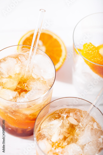 Cold brew coffee mocktail with orange peel and glass straw close-up.Glass with citrus espresso tonic on white background close-up.Refreshing summer non-alcoholic drink concept.Vertical orientation