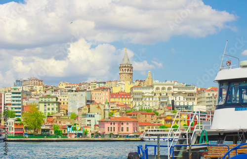 Galata Tower. View of famous historic landmark across Golden Horn. Galata bridge with fishermen. Popular tourist destination. Cloudy. Clear blue water. Turkey, Istanbul