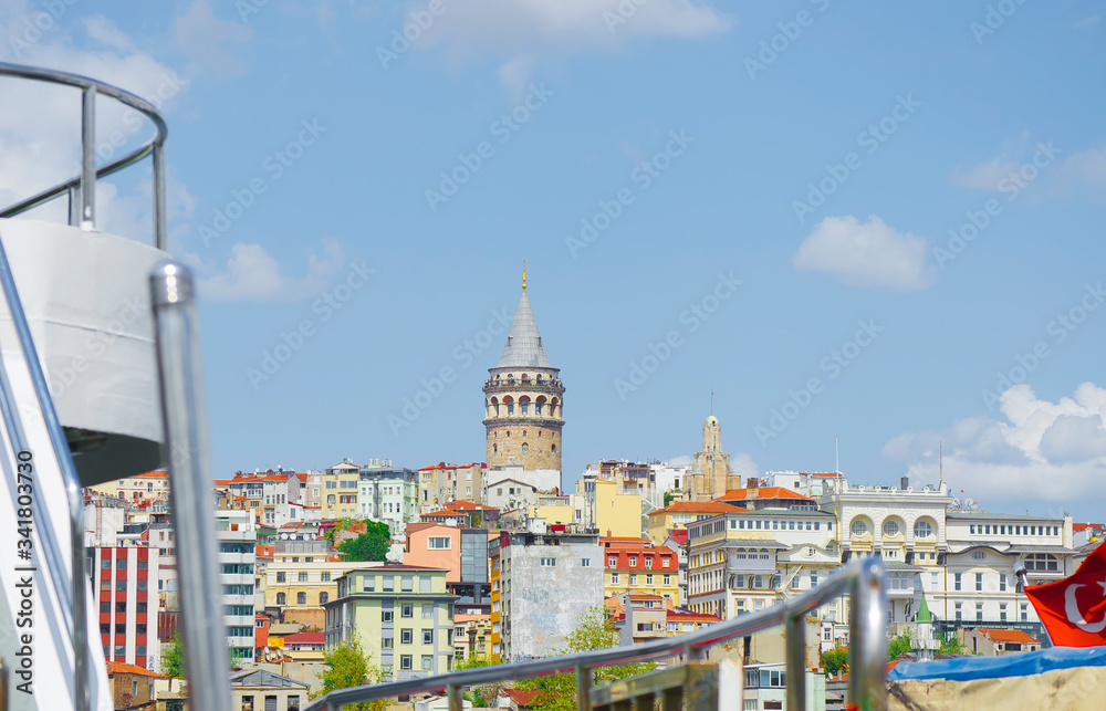 Galata Tower. View of famous historic landmark across Golden Horn. Galata bridge with fishermen. Popular tourist destination. Cloudy. Clear blue water. Turkey, Istanbul