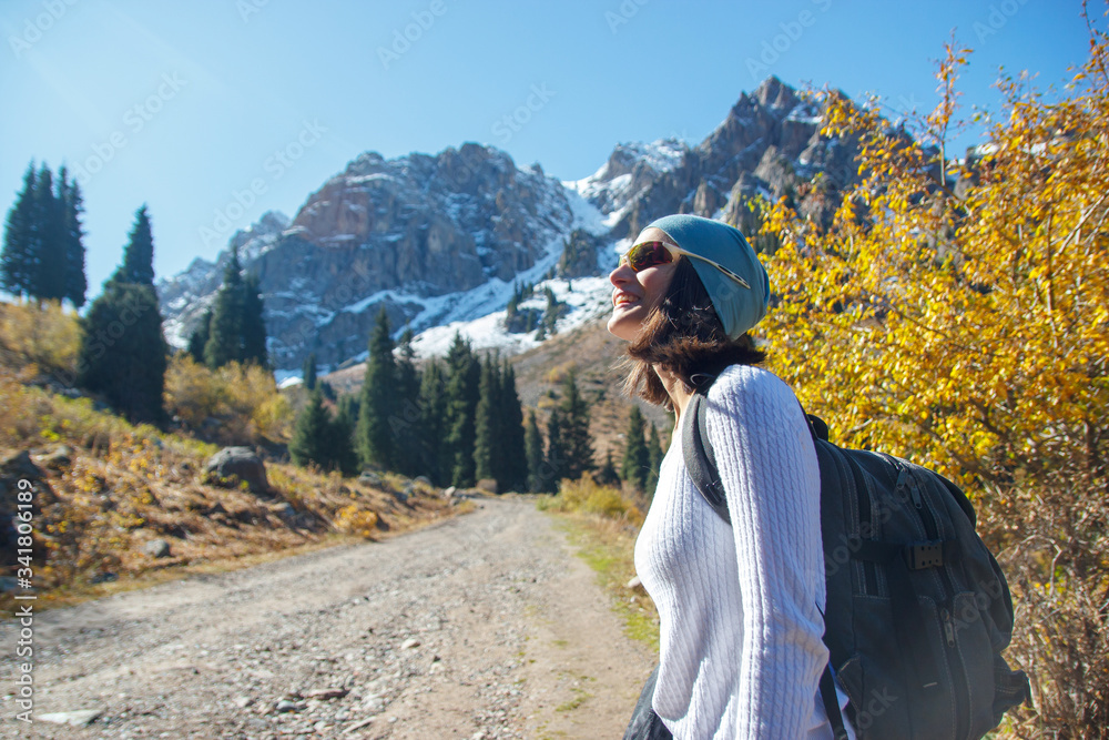 A smiling woman is looking up at the sky. Walk in the autumn in the mountains.