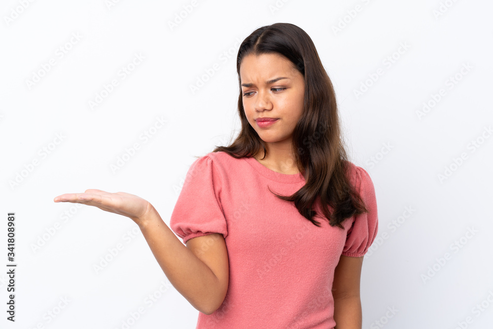 Young Colombian girl over isolated white background holding copyspace with doubts Young Colombian girl over isolated white background holding copyspace with doubts