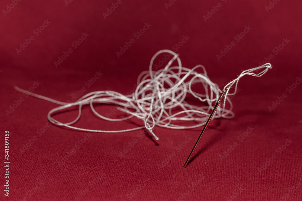 white thread on a needle with a red background white thread on a needle with a red background
