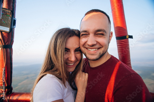 Happy smiling couple staying in air baloon basket at sunset. Couple first time on baloon flight