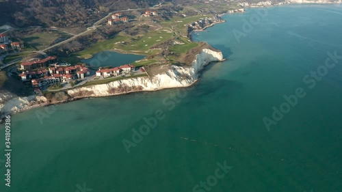 Panoramic video of picturesque landscape with green hills, golf fields and buildings near the rocky coastline of the Black sea, Thracian Cliffs golf and beach resort, Bulgaria. photo