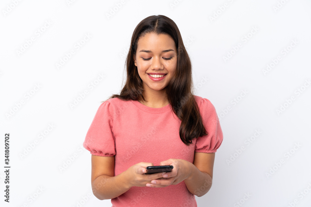 Young Colombian girl over isolated white background sending a message with the mobile Young Colombian girl over isolated white background sending a message with the mobile