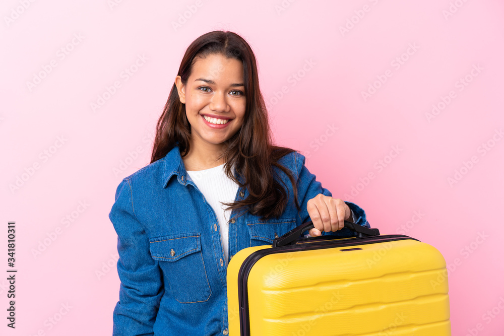 Traveler Colombian woman holding a suitcase over isolated pink background with surprise and shocked facial expression Traveler Colombian woman holding a suitcase over isolated pink background with surprise and shocked facial expression