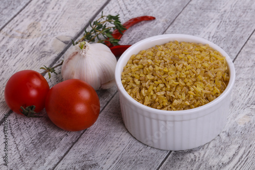 Raw bulgur in the bowl with tomatoes and garlic