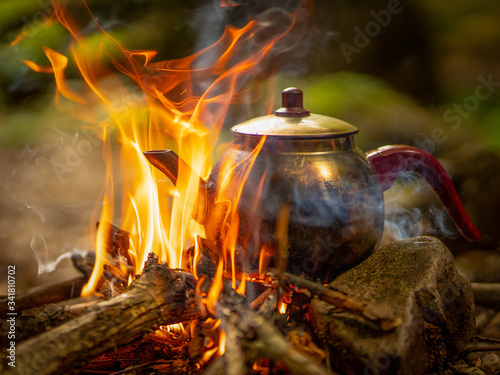 Making tea in the teapot in flames above the campfire