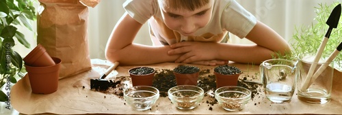  The child bent over the seeds planted in pots and looks with interest and waits for the germination.