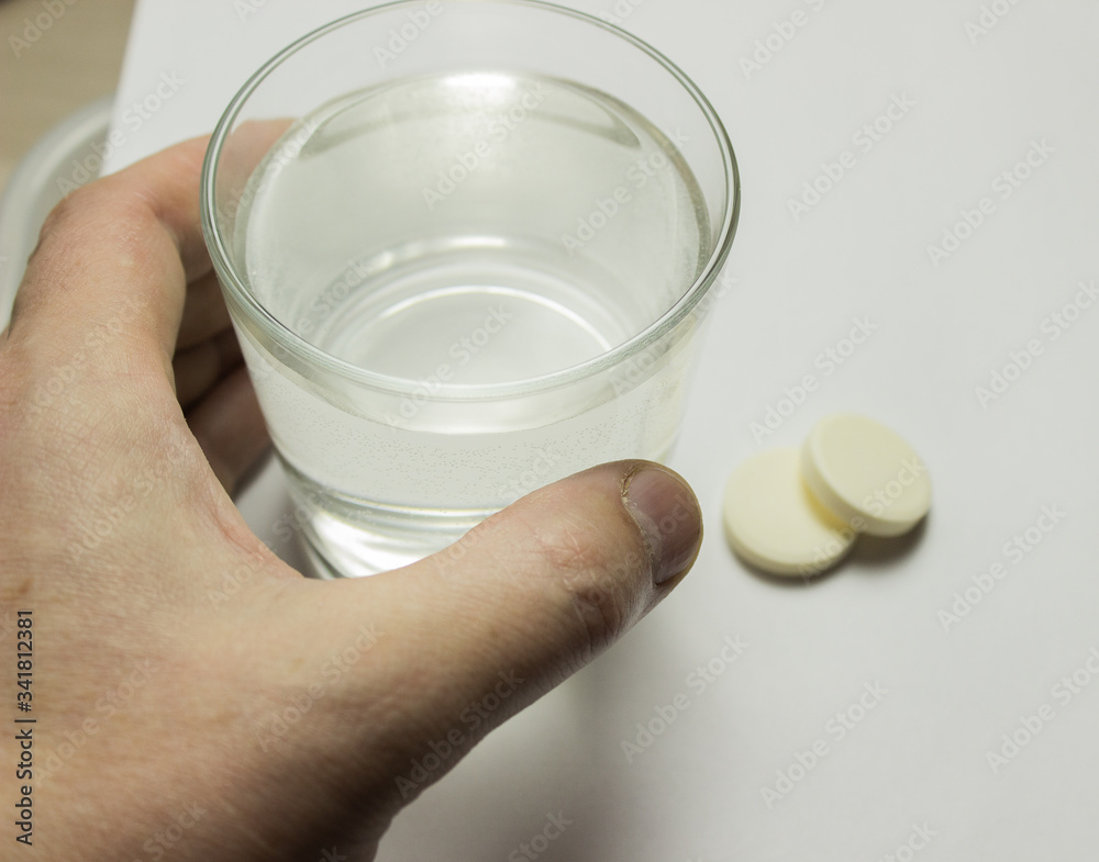 a glass of water on the table and tablets
