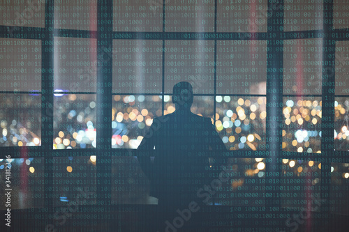 Man looks out window at night city in lights. Dual screen