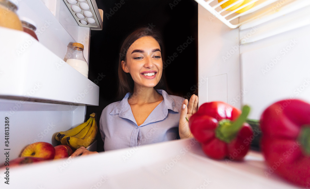Happy woman taking fresh vegetables from fridge Happy woman taking fresh vegetables from fridge