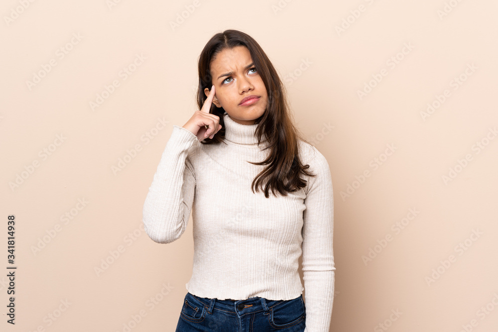 Young Colombian girl over isolated background making the gesture of madness putting finger on the head