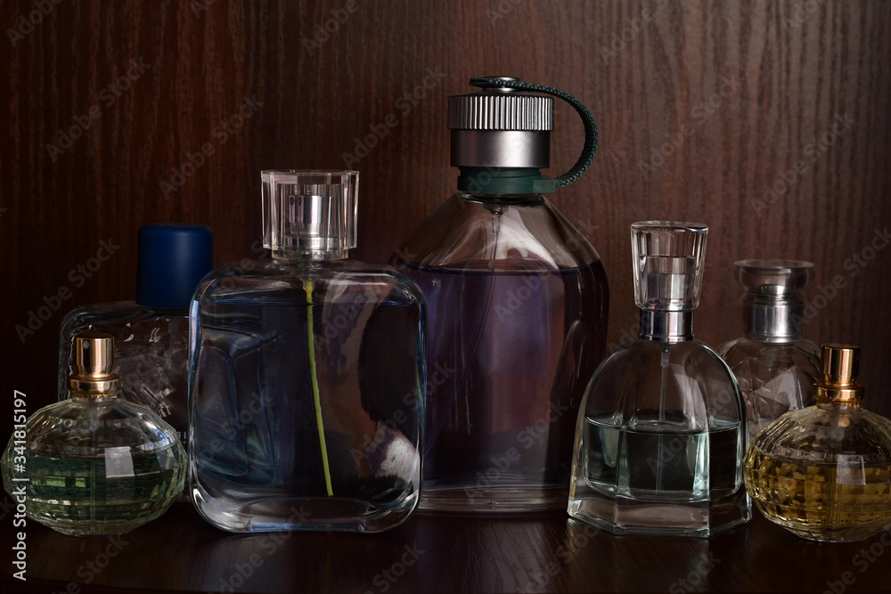 Glass bottles of perfumes of different sizes on the background of dark wooden shelf. Glass bottles of perfumes of different sizes on the background of dark wooden shelf.