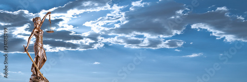 Bronze Themis statue - symbol of Justice - with a dramatic sky in the background